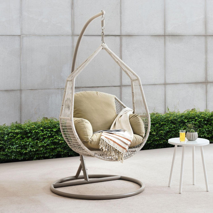 Cream outdoor hanging egg chair swing with plush removable cushion for patio relaxation.