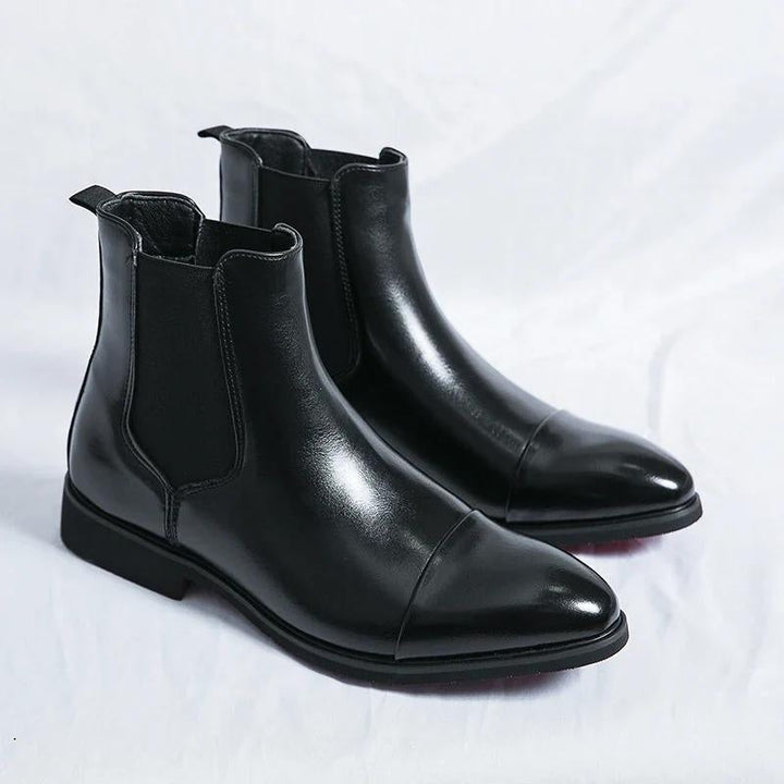Stylish men's slip-on ankle boots, black leather Chelsea design with eye-catching red sole detail.