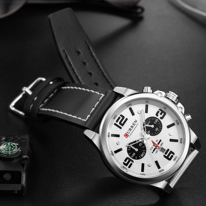 Close-up of a men's versatile chronograph watch with a black leather strap & white dial.