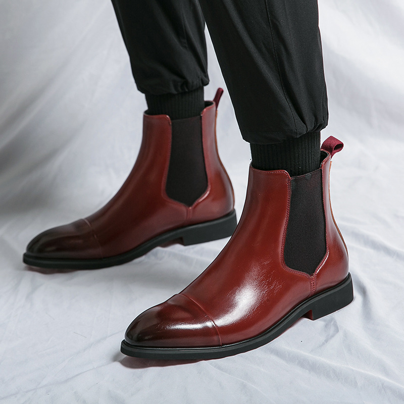 Classic men's dress shoes: sleek black leather Chelsea boots with a unique red sole feature.