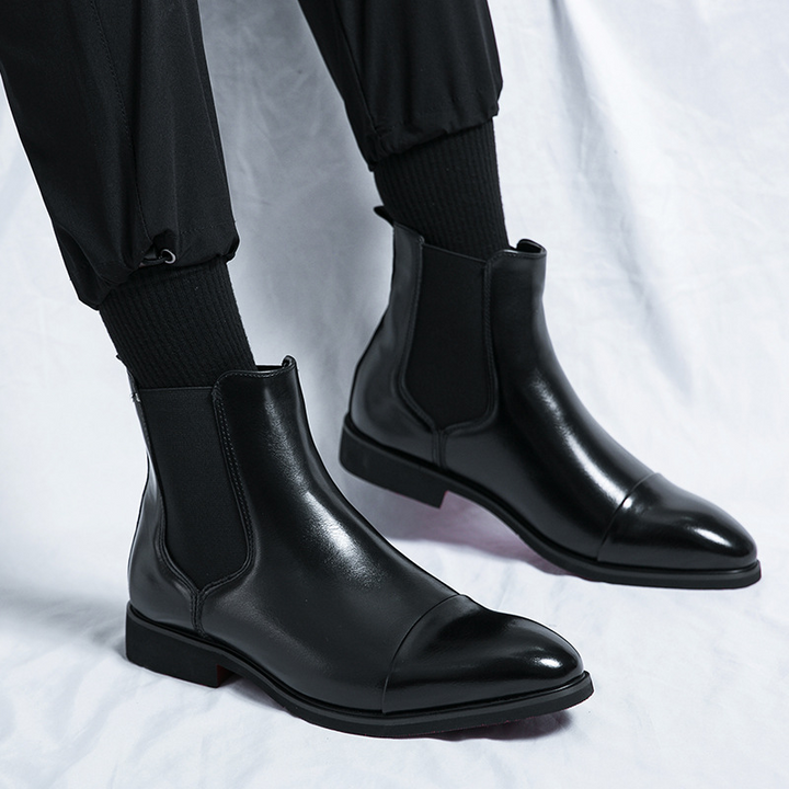 Modern men's fashion boots: sleek black Chelsea design, high-quality leather, iconic red sole accent.