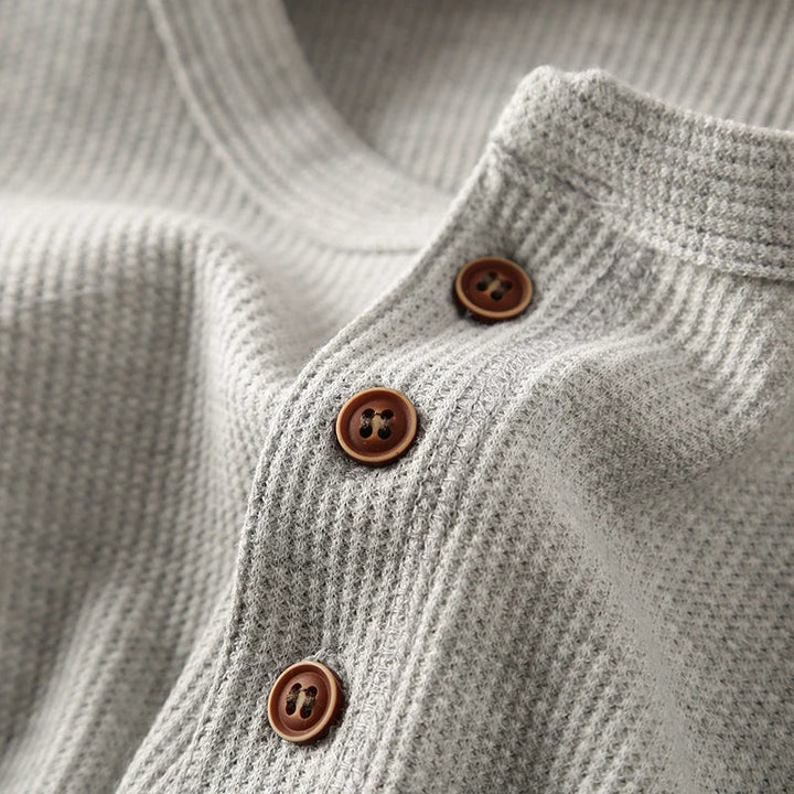 Close-up of the textured waffle knit fabric on a men's casual long sleeve shirt.