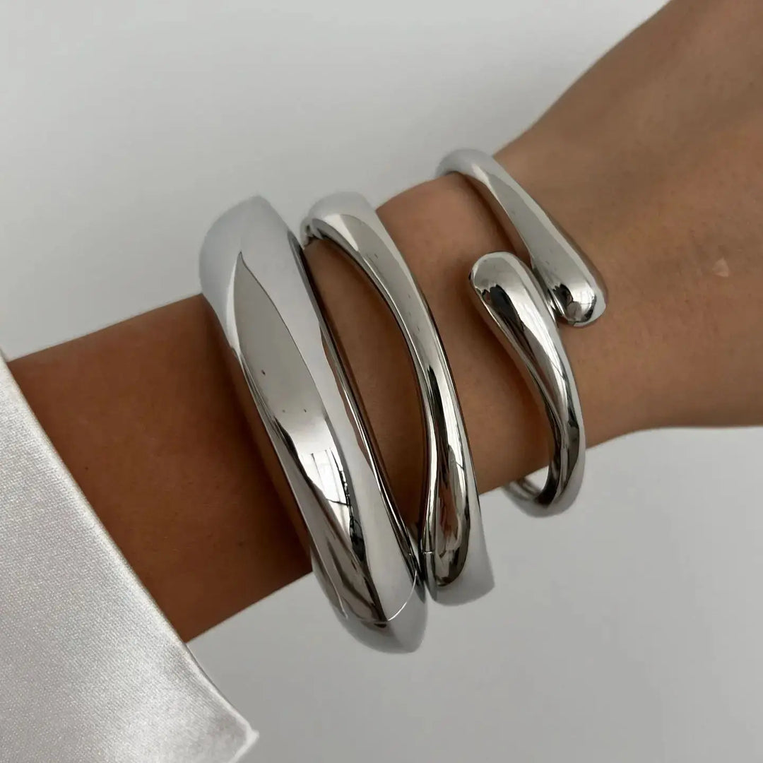Vintage style women's stackable bracelets in shimmering gold and silver, featuring elegant sculptural designs.