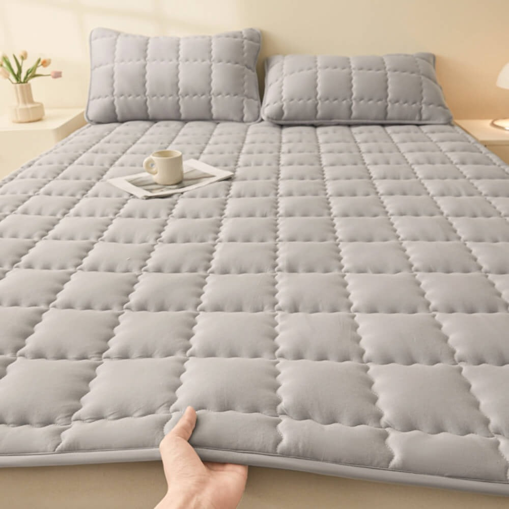Overhead shot of a luxurious quilted mattress topper spread on a bed, ready for restful sleep