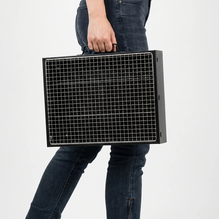 Foldable steel charcoal grill, compact design for easy transport and storage during outdoor cooking.