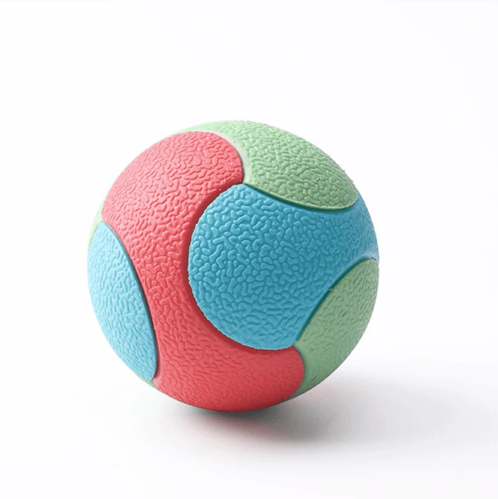Dog happily playing with a red durable interactive chew ball toy, showcasing its teeth cleaning features.