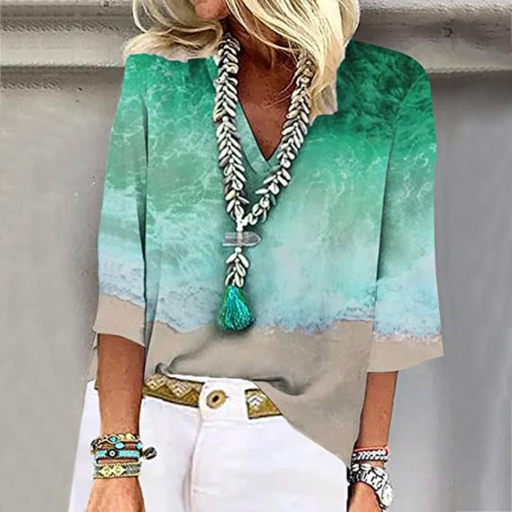 Elegante, luftige Damenbluse mit kristallblauen Nuancen und sandigen Tönen, V-Ausschnitt und weiten Ärmeln.