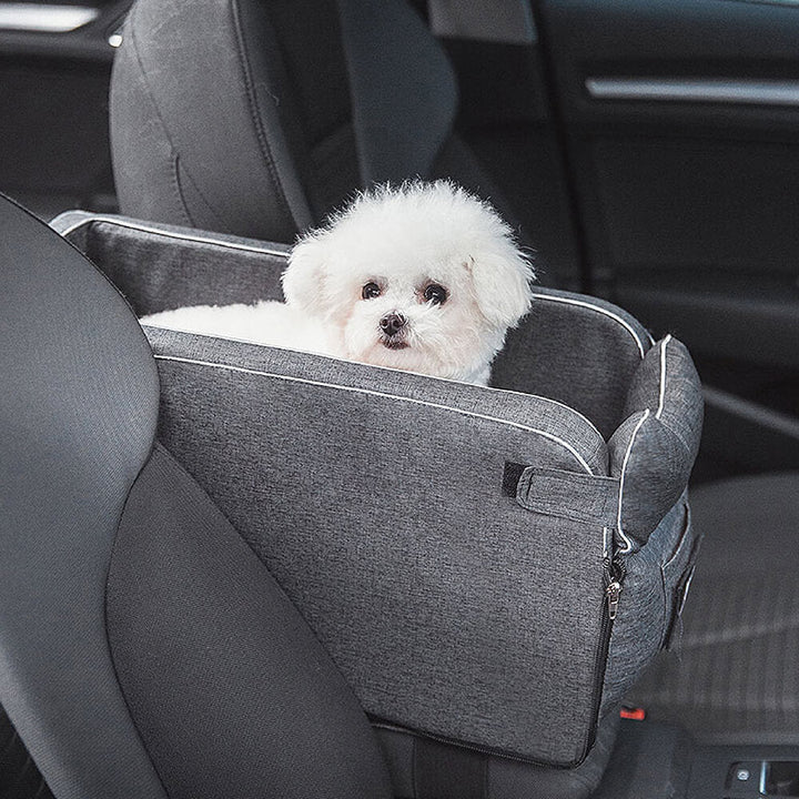 Small dog in a grey suede console car seat, elevated view for anxious pets