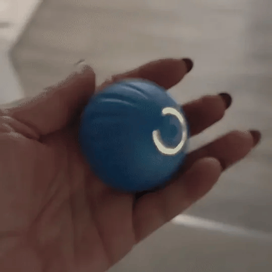 A cat batting at a glowing interactive pet ball. Motion-activated cat toy, rechargeable.