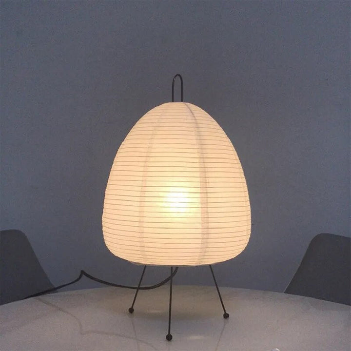 Japanische Tischlampe mit Reispapier, strahlt warmes, diffuses Licht aus, elegantes und zeitloses Design für Innenräume.
