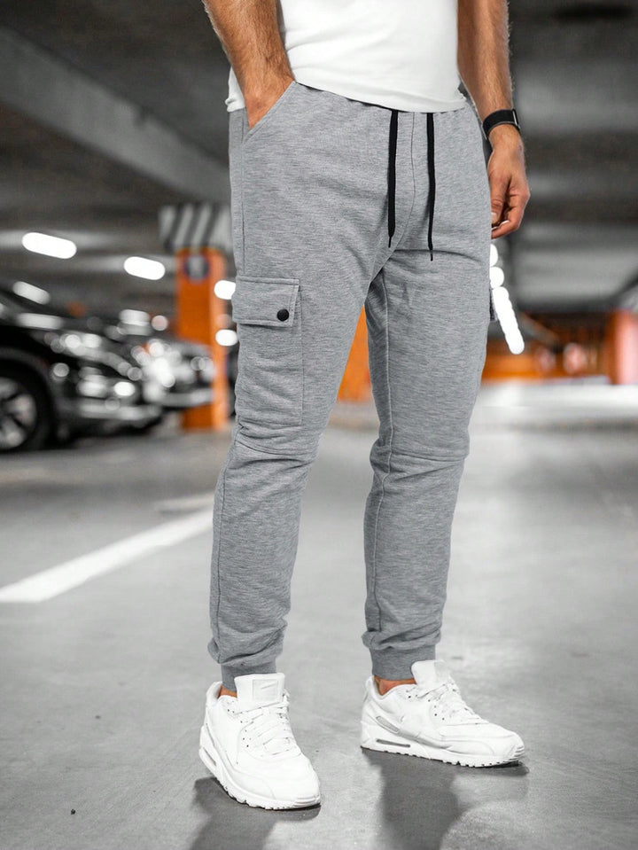 Slim-fit men's black jogger pants with cargo pocket, drawstring, and ribbed cuffs.