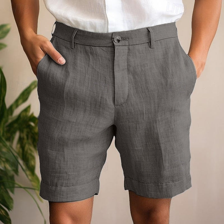 Man wearing stylish khaki relaxed fit summer shorts on a beach, ideal for vacation comfort.