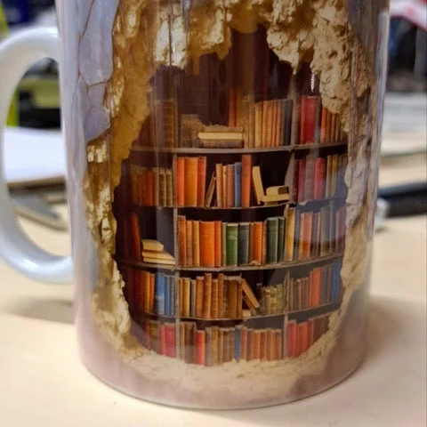 Functional ceramic coffee mug with a 3D library bookshelf design, perfect for book lovers to enjoy their drinks.