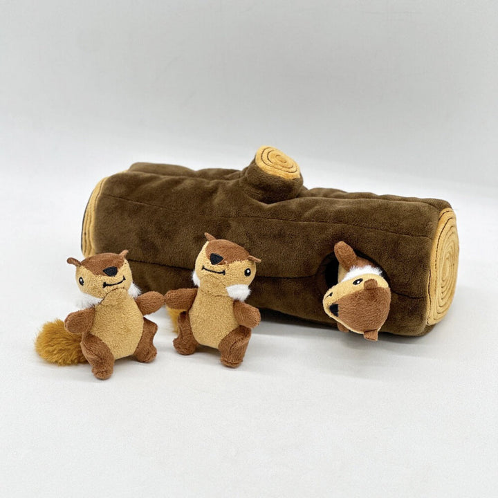 Close-up of a dog happily engaging with a plush squirrel from an interactive tree trunk toy