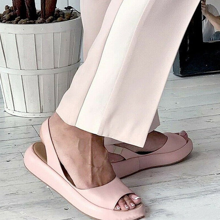 Rosa Damen Sommersandale mit elastischem Slip-on Design und niedrigem Absatz auf grauem Hintergrund.