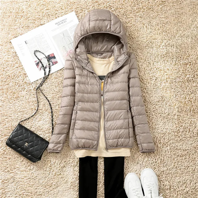 "Rosaroter Daunenmantel mit Kapuze und grauem Innentop, kombiniert mit schwarzen Jeans, für Damenmode."