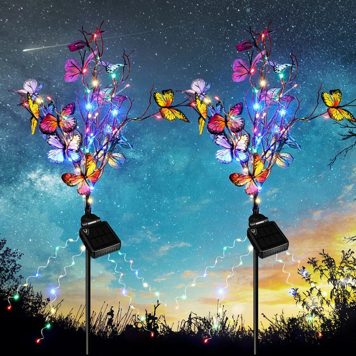 Two solar butterfly garden lights illuminating a lush garden at dusk, perfect for outdoor decor.