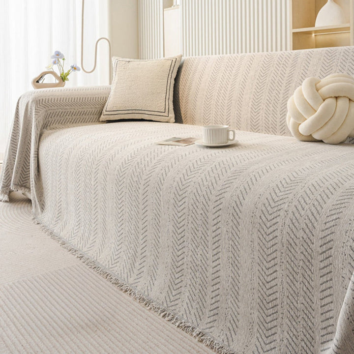 Beige chenille furniture protector draped over a sofa, showing its washable and durable design