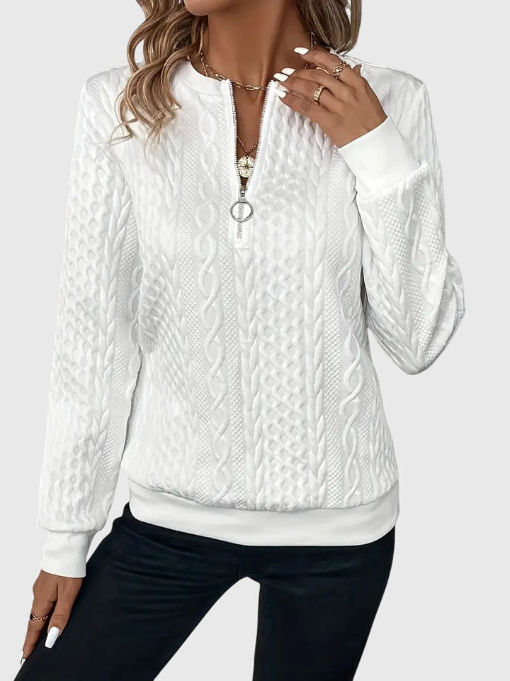 Close-up of cable knit texture on a white women's Harlow quarter-zip sweater. Cozy winter fashion.