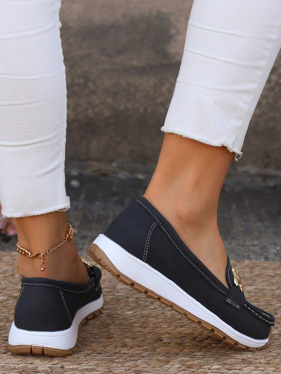 Pair of women's elegant gold chain flatform loafers. Round toe slip-on shoes offering comfort and fashion chic.