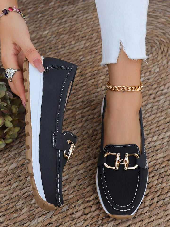 Black women's gold-trim horsebit loafers. Classic slip-on comfort, elegant footwear for any occasion.