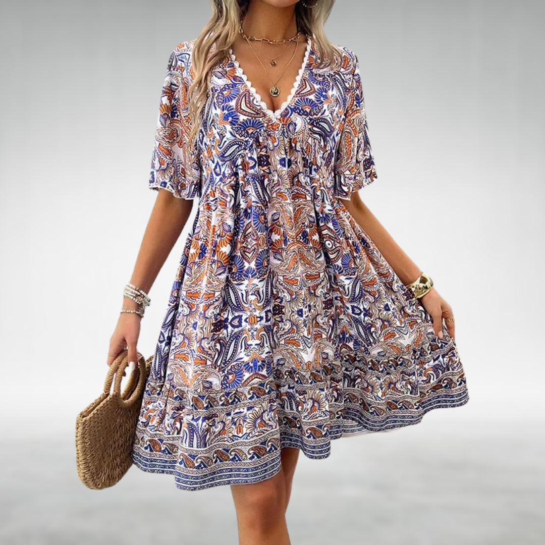 Flowy babydoll style women's boho mini dress featuring vibrant paisley print, lace trim, and ruffle hem.