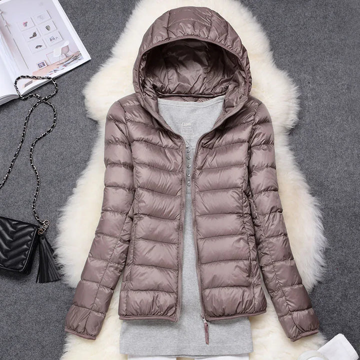 Women's travel jacket, ultralight insulated and hooded, offering warmth without bulk for winter.